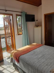 1 dormitorio con 1 cama y puerta corredera de cristal en Suítes Canola, en Ubatuba