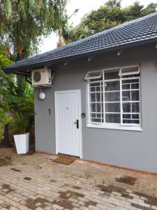a small house with a white door and a window at 21on2nd Avenue in Tzaneen