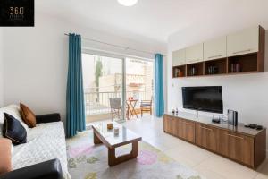 Una sala de estar con un sofá y un televisor de pantalla plana. en Beautiful, TOP NOTCH 1 BR APT just off the coast by 360 Estates, en St Paul's Bay