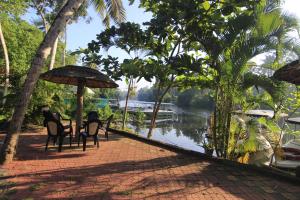 two people sitting at a table with an umbrella next to a river at Leela Backwater Inn in Trivandrum