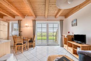 a living room with a dining table and a television at Schäferhof Dircks Fewo 4 in Westerhever