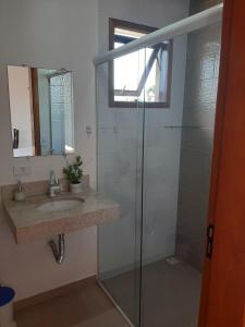 a bathroom with a shower and a sink and a mirror at Suítes Canola in Ubatuba