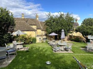 a yard with chairs and tables and umbrellas at Pass the Keys Charming 18th Century 4 bedroom cottage in Moreton in Marsh