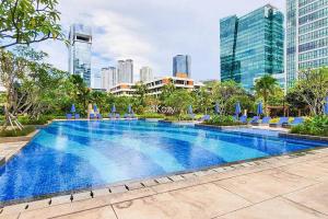 a large swimming pool with a city skyline in the background at MOIRA by Kozystay 2BR Great Location & Bathtub in Jakarta