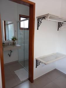 a bathroom with a glass shower and a sink at Suítes Canola in Ubatuba