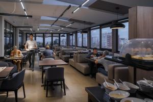 Ein Mann geht durch ein Restaurant, in dem Leute an Tischen sitzen. in der Unterkunft Solutel apartments-32 in Bischkek