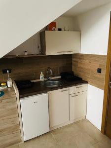 a small kitchen with white cabinets and a sink at Vuk apartment - Milmari Resort & Spa in Kopaonik