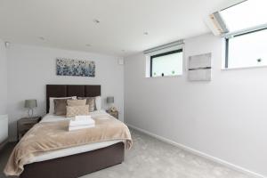 homely - Central London Camden Town Apartments في لندن: غرفة نوم بيضاء بها سرير ونوافذ