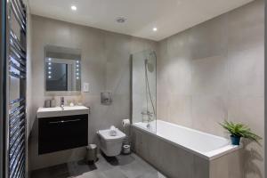 ein Badezimmer mit einer Badewanne, einem WC und einem Waschbecken in der Unterkunft homely - Central London Camden Town Apartments in London