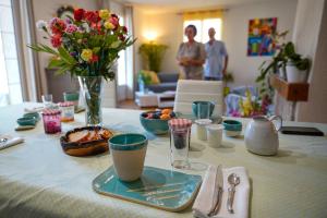 una mesa con un plato azul con un jarrón de flores en Aux Peupliers, en Le Malzieu-Ville