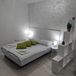 een witte slaapkamer met een bed met groene kussens bij Apartman Jevrejska Banja Luka in Banja Luka