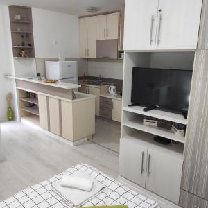 eine Küche mit weißen Schränken und einem Flachbild-TV in der Unterkunft Apartman Jevrejska Banja Luka in Banja Luka