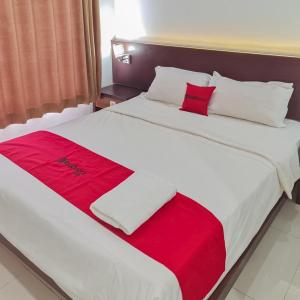 een slaapkamer met 2 bedden met rode en witte lakens bij RedDoorz Plus at Hotel Royal Palangka Raya in Palangkaraya