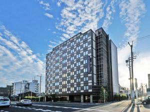 un edificio alto en una calle de la ciudad con un cielo en CHISUN PREMIUM Kyoto Kujo, en Kioto