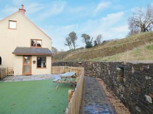a house with a stone wall and a picnic table at Nant Moel Isaf Farm in Swansea