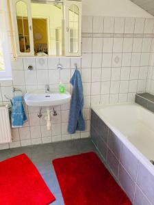 a bathroom with a white tub and a sink and red mats at Clarkes Apartments in Leopoldshöhe