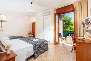 a bedroom with a bed and a table and a window at Hotel Horizonte in Bibione