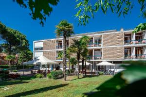 un bâtiment avec des palmiers en face de celui-ci dans l'établissement Hotel Horizonte, à Bibione