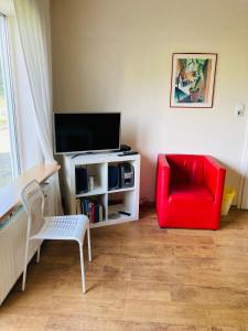 uma sala de estar com uma cadeira vermelha e uma televisão em Clarkes Apartments em Leopoldshöhe