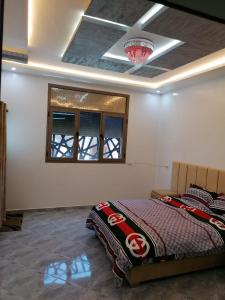 a bedroom with a bed and a ceiling with a chandelier at Appartement lux dakhla in Dakhla