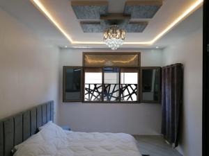 a bedroom with a bed and a chandelier and a window at Appartement lux dakhla in Dakhla