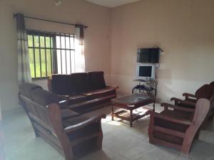 ein Wohnzimmer mit einem Sofa, Stühlen und einem TV in der Unterkunft Villa ETE-D in Bohicon