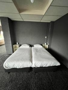 um quarto com uma cama grande e lençóis brancos em Hotel de Raket em Rogat