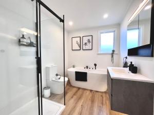 uma casa de banho branca com uma banheira e um lavatório em Central Villa, Close to everything! By KOSH BNB em Hamilton