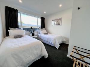 1 dormitorio blanco con 2 camas y ventana en Central Villa, Close to everything! By KOSH BNB en Hamilton