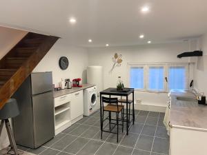 a kitchen with a refrigerator and a table in it at Chantignolle, proche aéroport in Tillé