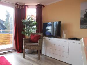 - un salon avec une télévision et une chaise avec un oreiller rouge dans l'établissement Chalet Platzhirsch, à Braunlage