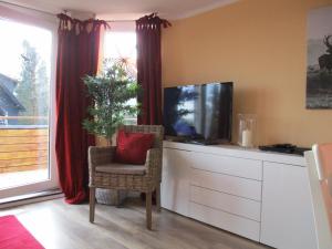 a living room with a tv and a chair with a red pillow at Chalet Platzhirsch in Braunlage