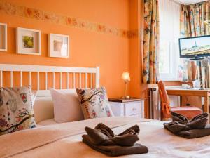 een slaapkamer met oranje muren en een bed met bruine handschoenen erop bij Zimmer Nr 2 im Haus Sabine in Braunlage