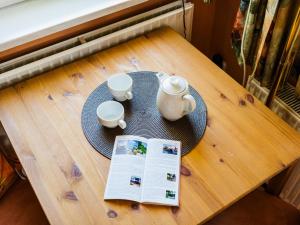 ein Tisch mit zwei Tassen und einer Zeitung darauf in der Unterkunft Haus Sabine - Zimmer 2 in Braunlage