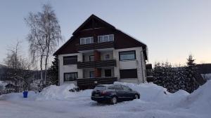 ブラウンラーゲにあるOle's BergSuiteの雪に覆われた家の前に停められた車