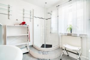 een witte badkamer met een douche en een stoel bij JermersteinSonne in Braunlage
