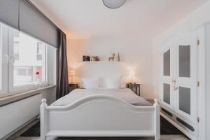 a white bedroom with a white bed and a window at Harzer Auszeit in Braunlage