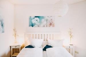 ブラウンラーゲにあるHarz Zeit Braunlageの白いベッドルームのベッド2台、壁に絵が描かれています。