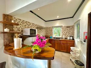 une cuisine avec une table en bois et des fleurs. dans l'établissement Seaside Self Catering, à Mahé