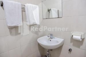 a white bathroom with a sink and towels at Graha Sartika Hotel RedPartner in Bandung +16 photos