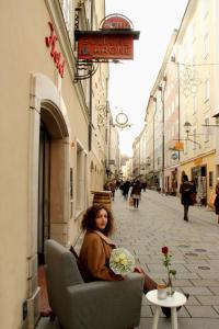 uma mulher sentada numa cadeira numa rua em Hotel Krone 1512 em Salzburgo