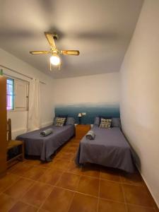 een kamer met 2 bedden en een plafondventilator bij La Casa del Abuelo Jose in Marmolejo