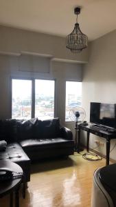a living room with a black leather couch and a television at 2 Bedroom Condo Unit in Manila