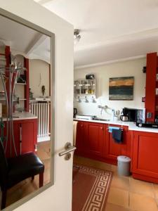 a kitchen with red cabinets and a mirror at Ahoi Husum, anlegen und wohlfühlen in Husum