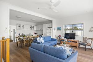 a living room with a blue couch and a table at Seaside Beach House in Burrill Lake