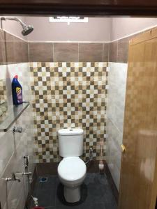 a bathroom with a toilet and a tiled wall at Whole house - 2 bedrooms for family with kids and Free Wifi in Changlun