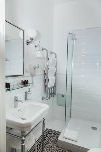 a white bathroom with a sink and a shower at Sherlock Apartments in Riga