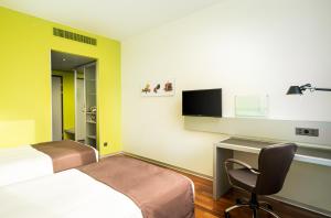 a hotel room with a bed and a desk and a tv at Holiday Inn Bern Westside by IHG in Bern +77 photos