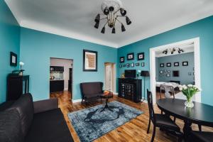 ein Wohnzimmer mit blauen Wänden sowie einem Tisch und Stühlen in der Unterkunft Sherlock Apartments in Riga + 12 Fotos