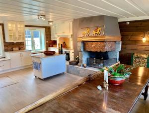 a kitchen with a living room with a fireplace at Traditional timber farm with Sauna & Wi-Fi in Baukål